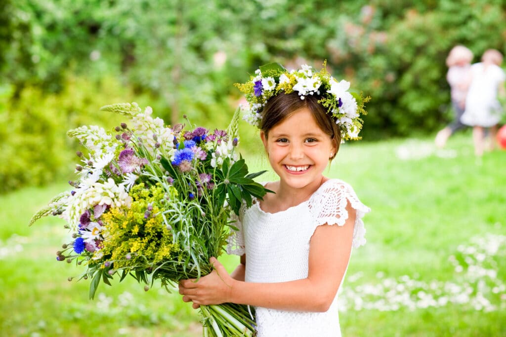 A young girl with a beautiful flower wreath celebrating swedish Midsummer